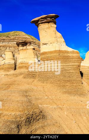 Ein felsiger Hügel mit einem großen Felsen auf der Spitze. Der Felsen ist wie ein Pilz geformt. Der Himmel ist klar und blau Stockfoto