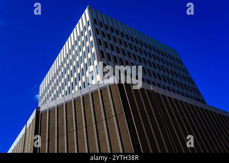 Ein großes, modernes Gebäude mit vielen Fenstern und einem klaren blauen Himmel im Hintergrund. Das Gebäude ist sehr hoch und hat ein schlankes, modernes Design Stockfoto