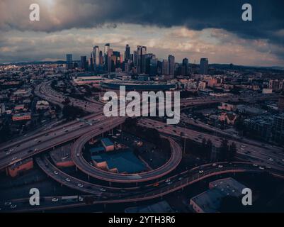 JANUAR 2024, LOS ANGELES, CA. - Luftaufnahme der Skyline VON LA bei Sonnenuntergang mit der Kreuzung von Harbor Freeway 110 und Interstate Highway 10 mit Verkehr Stockfoto