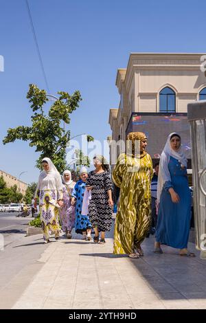 Samarkand, Usbekistan - 6. Juli 2024: Frauen gehen in traditioneller Kleidung auf den Straßen der Stadt Stockfoto