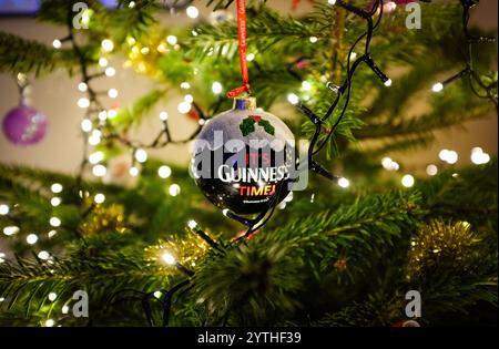 Echter Tannenbaum mit Lichtern und einer IT's Guinness Time Kugel Dekoration für die Weihnachtszeit , Dezember 2024 in Großbritannien : Credit Simon Dack / Stockfoto