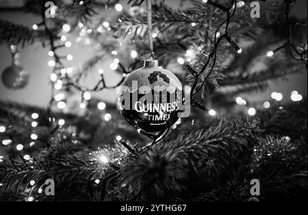 Echter Tannenbaum mit Lichtern und einer IT’s Guinness Time Kugeln für die Weihnachtszeit , Dezember 2024 in Großbritannien : Stockfoto