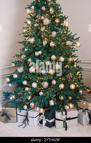 Ein wunderschön dekorierter Weihnachtsbaum steht in einem gemütlichen Raum, geschmückt mit Lichtern und Ornamenten. Darunter warten zahlreiche gewickelte Geschenke, die noch aufwerten Stockfoto