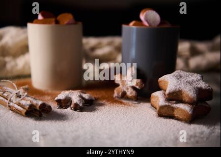 Warme Winterszene mit heißer Schokolade mit Marshmallows und Lebkuchenpudern auf einem Tisch. Stockfoto