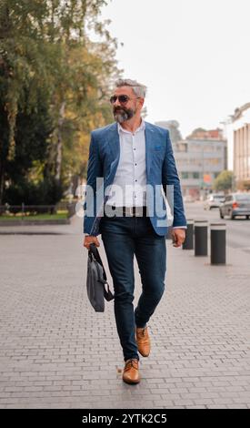 Ein reifer Mann in eleganten, stilvollen Kleidern, der durch die Straße der Stadt spaziert. Hochwertige Fotos Stockfoto