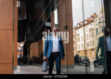 Ein reifer Mann in eleganten, stilvollen Kleidern, der durch die Straße der Stadt spaziert. Stockfoto