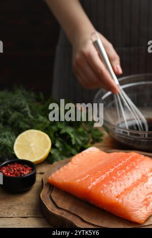 Frau, die Sojamarinade für Lachsfilet am Holztisch macht, Nahaufnahme Stockfoto