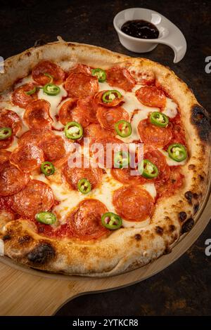 Nahaufnahme von Pizza mit geschmolzenem Mozzarella und in Scheiben geschnittenen Jalapenos, serviert mit Pizzasauce Stockfoto