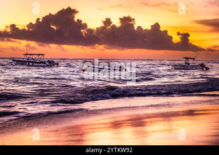 Karibischer Sonnenaufgang - Dominikanische Republik Punta Cana - farbenfrohes Meer und wunderschöner Sonnenaufgang Strand mit Booten und goldene Sonne auf Sand Stockfoto