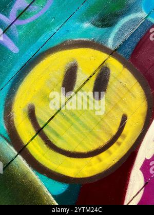 Ein gesprühtes Smiley-Emoji an einer Holzwand Stockfoto