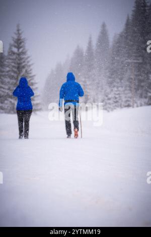 Ein paar Reisende wandern auf dem verschneiten Bergwaldpfad Wandern Winterurlaub Abenteuer Reise. Stockfoto