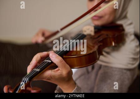 Ein detaillierter Blick auf die Hände einer Frau, die fachmännisch eine Geige spielt und musikalisches Talent und Konzentration zeigt. Stockfoto