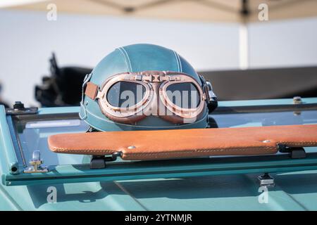 Blaugrüner Oldtimer-Helm und Brille an einem alten Auto Stockfoto
