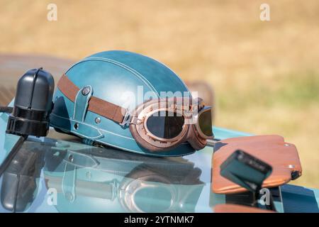 Blaugrüner Oldtimer-Helm und Brille an einem alten Auto Stockfoto