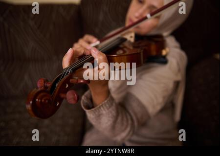 Eine detaillierte Ansicht einer Frau, die Geige spielt, die ihren Fokus und ihre Präzision erfasst. Das Bild hebt die komplizierten Bewegungen der Saiten hervor, die in gesetzt sind Stockfoto