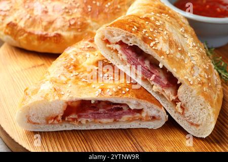 Stücke von Calzone Pizza serviert auf Holztisch, Nahaufnahme Stockfoto