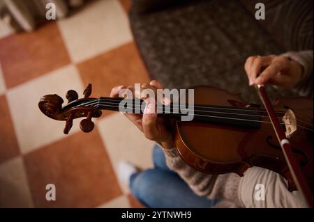 Eine detaillierte Ansicht einer Person, die Geige spielt und sich auf Technik und Emotionen konzentriert, in einer gemütlichen Wohnumgebung. Stockfoto