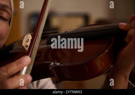 Detaillierte Ansicht der Hände eines Musikers, der gekonnt eine Geige spielt, wobei die Kunstfertigkeit und der Fokus, die bei der Musikaufführung erforderlich sind, erfasst werden. Stockfoto