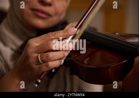 Eine detaillierte Ansicht einer Frau, die Geige spielt, wobei ihre Hände und das Instrument hervorgehoben werden, wobei Hingabe und Kunstfertigkeit während einer musikalischen Aufführung gezeigt werden Stockfoto