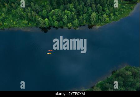 Top Luftaufnahme von gelben und roten Kajaks mit zwei Personen Paddelkayak schwimmend durch Bergsee umgeben von Kiefernwäldern in Norwegen. Aktive Peo Stockfoto