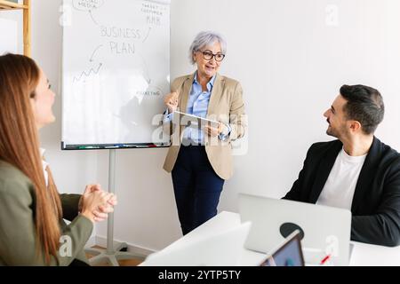 Leitende Geschäftsfrau, die eine Präsentation mit ihrem Team im Büro leitet Stockfoto