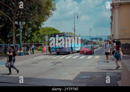 San Jose, Costa Rica, 27.4,2023: Leute am Busbahnhof warten, in der Nähe des Hauptplatzes. Typische Hektik des gemeinsamen sonnigen Tages Stockfoto