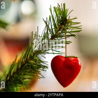 Nahaufnahme einer roten Herzdekoration, die an einem Weihnachtsbaum hängt Stockfoto