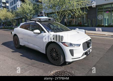 Tempe, USA. Dezember 2024. Ein Waymo selbstfahrendes Jaguar I-PACE Elektrofahrzeug wird am 6. Dezember 2024 an einer roten Ampel in Tempe, Arizona, angehalten. Waymo arbeitet mit Usern von Uber Eats in Phoenix, Chandler, Mesa und Tempe zusammen und arbeitet mit ausgewählten Händlern in diesen Städten zusammen. Darüber hinaus hat Waymo sein Servicegebiet auf 90 Quadratkilometer Metro Phoenix für Waymo One-Fahrer erweitert und ist damit das größte autonome Ride-Hagel-Gebiet in den Vereinigten Staaten. (Foto: Alexandra Buxbaum/SIPA USA) Credit: SIPA USA/Alamy Live News Stockfoto