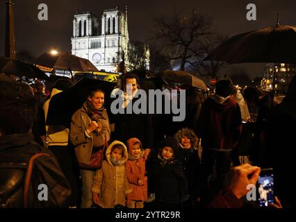 Paris, Frankreich. Dezember 2024. Die Leute posieren für Fotos vor der restaurierten Kathedrale Notre-Dame de Paris im Regen in Paris, Frankreich, 7. Dezember 2024. Fünf Jahre nachdem sie von einem Feuer verwüstet worden war, wurde die restaurierte Kathedrale Notre-Dame de Paris am Samstag offiziell mit einer großen Einweihungszeremonie wieder eröffnet, an der sowohl Führer der Welt, Gläubige als auch Nichtgläubige teilnahmen. Quelle: Gao Jing/Xinhua/Alamy Live News Stockfoto