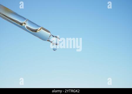 Nahaufnahme eines Tropfens aus einer Pipette gegen einen klaren blauen Himmel Stockfoto