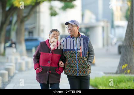 Chinesin in ihren 70ern und ihr Enkel, Mann in seinen 30ern, spazieren im Qingpu-Viertel von Shanghai, China, während der kalten Wintersaison entlang des Flusses. Stockfoto