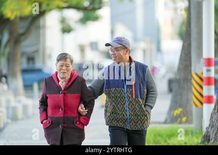 Chinesin in ihren 70ern und ihr Enkel, Mann in seinen 30ern, spazieren im Qingpu-Viertel von Shanghai, China, während der kalten Wintersaison entlang des Flusses. Stockfoto