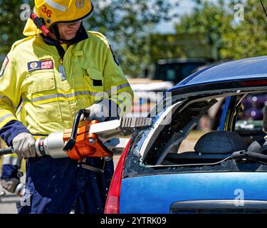 Motueka, Tasman District, Aotearoa / Neuseeland - 7. Dezember 2024: Ein Feuerwehrmann schneidet ein zerstörtes Fahrzeug auf, um mit den Kiefern des Lebens zu retten. Stockfoto