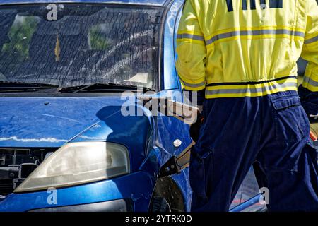 Motueka, Tasman District, Aotearoa / Neuseeland - 7. Dezember 2024: Ein Feuerwehrmann schneidet ein abgestürztes Auto auf, um mit einem Werkzeug Jaws of Life zu retten Stockfoto