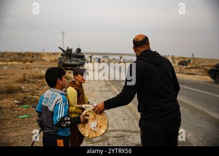 Hama, Syrien. Dezember 2024. Syrische Kinder inmitten von Militärfahrzeugen, die von syrischen Regierungstruppen verlassen wurden, als syrische Oppositionstruppen in die Stadt Hama eindringen. Seit dem 27. November sind syrische Oppositionsgruppen unter der Führung von Hayat Tahrir al-Sham stetig aus ihrer Festung in Idlib heraufgewachsen und haben große strategische Gebiete von der syrischen Regierung von Bashar Al-Assad eingenommen. Credit: IMAGESLIVE/Alamy Live News Stockfoto