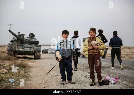 Hama, Syrien. Dezember 2024. Syrische Kinder inmitten von Militärfahrzeugen, die von syrischen Regierungstruppen verlassen wurden, als syrische Oppositionstruppen in die Stadt Hama eindringen. Seit dem 27. November sind syrische Oppositionsgruppen unter der Führung von Hayat Tahrir al-Sham stetig aus ihrer Festung in Idlib heraufgewachsen und haben große strategische Gebiete von der syrischen Regierung von Bashar Al-Assad eingenommen. Credit: IMAGESLIVE/Alamy Live News Stockfoto