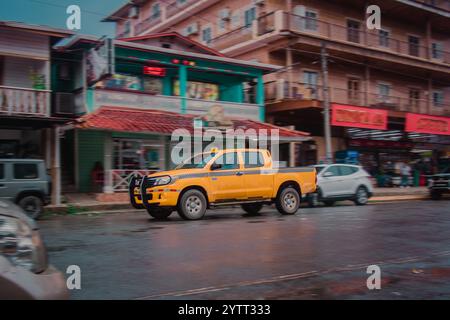 Typisches gelbes Taxi auf den bocas del toro Inseln in Panama. Big SUV Abholung durch die regnerischen Straßen von bocas, Blick auf die Straße und das urbane Leben Stockfoto