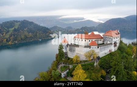 Luftdrohenszene der mittelalterlichen Burg Bled, die auf einer Klippe mit Blick auf den See Bled und die julischen alpen im Herbst, slowenien, thront Stockfoto