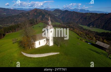 Drohnenblick auf die Kirche St. Tomaz selca, die auf einem grünen Hügel in der slowenischen Landschaft steht. Stockfoto