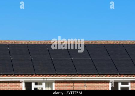 Solarpaneel-Array auf dem Dach eines Wohnhauses mit klarem blauem Himmel installiert Stockfoto