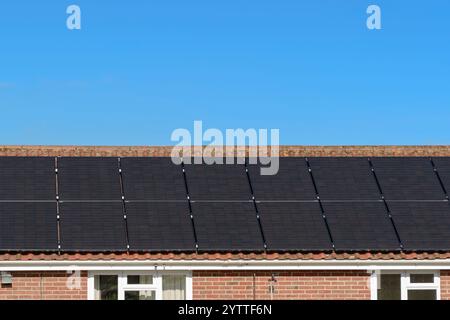 Solarpaneel-Array auf dem Dach eines Wohnhauses mit klarem blauem Himmel installiert Stockfoto