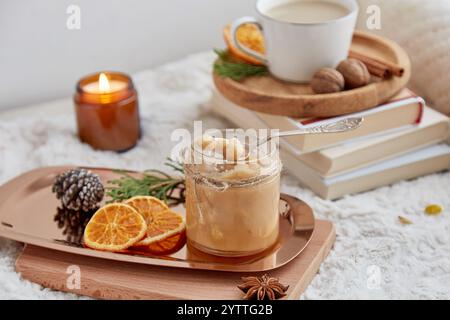 Hausgemachte Nuss gesalzenes Karamell in einem Glas mit einer Tasse Kaffee in einem gemütlichen Zuhause. Ästhetisches Weihnachtsfrühstück Stockfoto