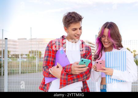 Zwei Schüler lächeln und benutzen im Freien Smartphones Stockfoto