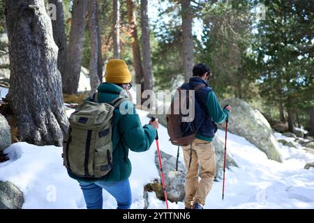 Junges, nicht erkennbares Paar, das auf einem verschneiten Berg wandert und das Winterabenteuer genießt. Stockfoto