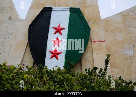 7. Dezember 2024: Hama, Syrien. Dezember 2024. Die syrische Oppositionsflagge ist auf einer adlerförmigen Mauer in Hama gemalt, nachdem Oppositionskämpfer die Stadt von den syrischen Regierungstruppen eingenommen haben. Seit dem 27. November sind syrische Oppositionsfraktionen unter der Führung von Hayat Tahrir al-Sham rasch aus ihrer Festung in Idlib vorgezogen und haben große strategische Gebiete von der syrischen Regierung von Baschar Al-Assad eingenommen. Die Rebellen haben ihre andauernde Militäroperation als „Abschreckung der Aggression“ bezeichnet (Credit Image: © Juma Mohammad/IMAGESLIVE via ZUMA Press Wire). Nicht für kommerzielle ZWECKE Stockfoto