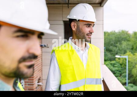 Ingenieure, die Baustellen mit Warnweste und Schutzhelm inspizieren Stockfoto