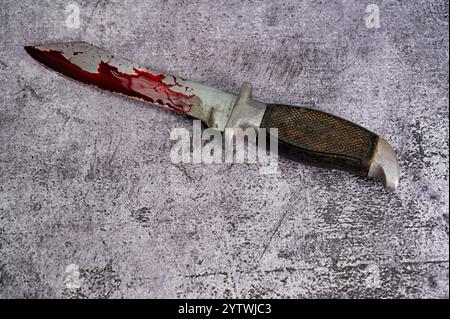Ein mit Blut bedecktes Kampfmesser liegt auf einer Marmoroberfläche. Hochwertige Fotos Stockfoto