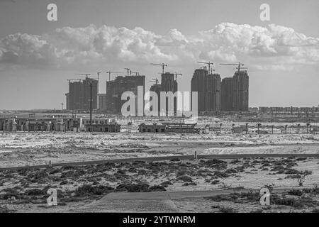 Schwarzweiß-Bild von Hochhäusern im Bau in New El Alamein City, Ägypten. Der Kontrast hebt die städtische Entwicklung gegen die Desertion hervor Stockfoto