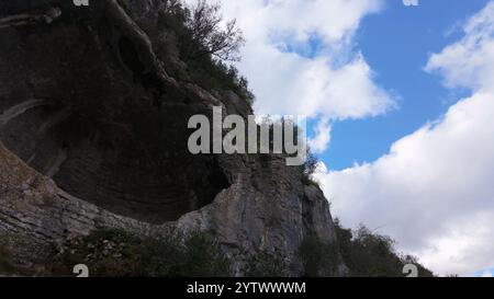 Buracas do Casmilo in Condeixa - Portugal. Alte Kalksteinhöhlen in einem zerklüfteten Hügel mit mehreren natürlichen Höhlenöffnungen im Grün Stockfoto