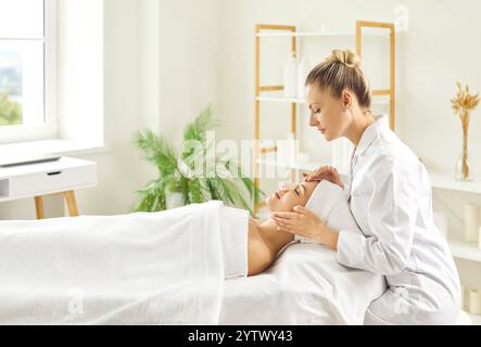 Kosmetologische Frau, die sich auf die Massage für ein junges Mädchen im Schönheitssalon vorbereitet. Stockfoto